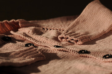 Fototapeta na wymiar Knitted pink handmade sweater on a dark background