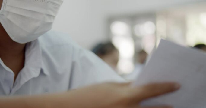 Slow motion scene of Asian high school students in a white school uniform wearing the masks to do final exams in the midst of Coronavirus disease 2019 (COVID-19) epidemic.