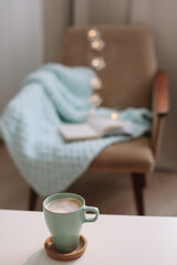 Cozy home interior with cup of coffee, book and armchair