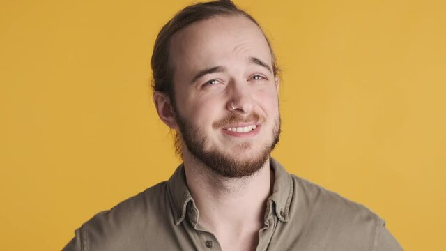 Portrait of young bearded man waving no gesture disagree with your opinion over yellow background