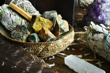A close up image of several different smudge bundles with selenite and healing crystals in an...