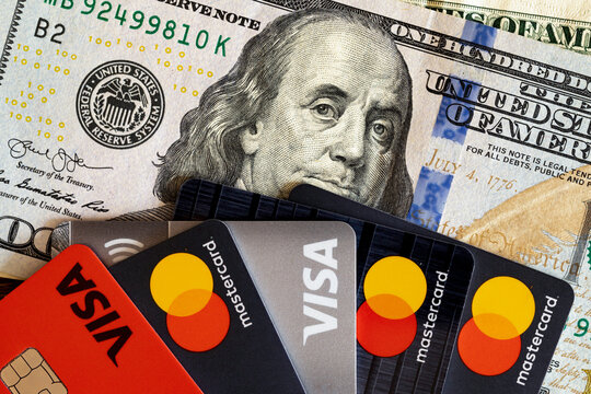 VISA and Master Card bank cards on a 100 US dollars banknote. VISA American multinational financial services corporation. MasterCard International payment system. Voronezh, Russia - March 5, 2021