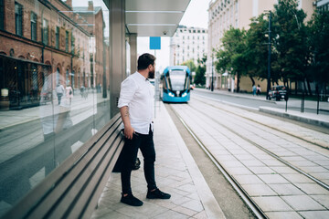 Stylish male looking at arriving tramway on empty city street © BullRun