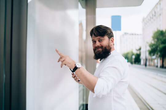 Smiling young man standing on tram stop and looking at camera