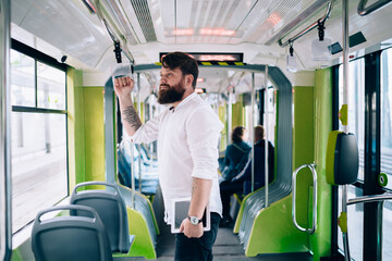 Focused bearded man with tablet in train