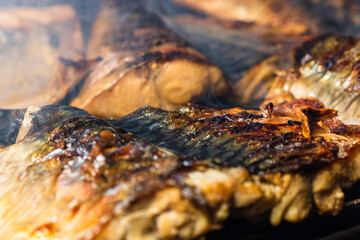 Grilled mackerel fish with smoke on a charcoal barbecue grill.