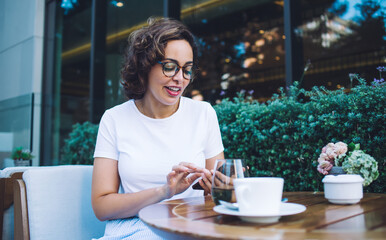 Smiling woman using smartphone in outdoor restaurant