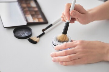 Womens cosmetics brush for applying makeup. Female hands apply white powder to the skin with a makeup brush. girl applying makeup with makeup tools