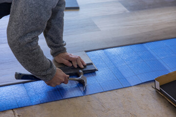 Renovation works craftsman improvement man with a using hammer the installing laminate flooring