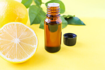 Aromatherapy oil for massage and treatments. Lemon oil in a bottle with an open lid on a yellow background.