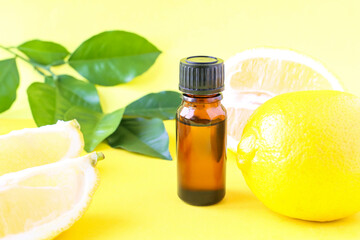 Lemon oil on a bright background and yellow citrus fruits. Aromatherapy, aroma. The use of oil in medicine.