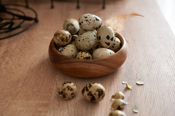 Fototapeta na wymiar quail eggs in a wooden bowl painted with a feather on a woodentable. Easter concept