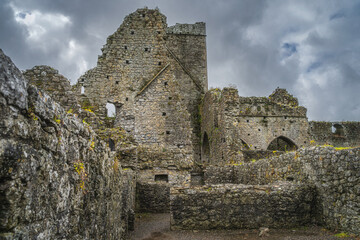Fototapeta na wymiar Closeup on exterior walls of ruined and abandoned Hore Abbey with dramatic storm sky. Located next to Rock of Cashel castle, County Tipperary, Ireland