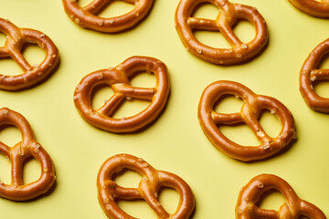 mini salted pretzels on yellow background. hard crackers or snacks. top view, above                                                 