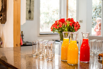 Glass of water with yellow and red juices and flowers
