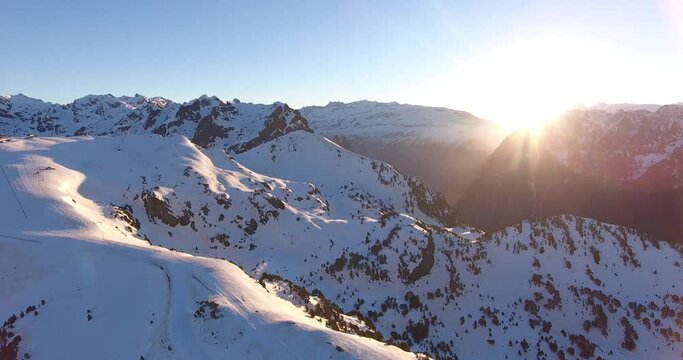 Alps in the Chamrousse region of France with sunrise behind mountain peaks, Aerial pan right shot