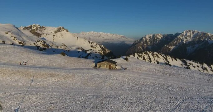 Men standing near cabin at Chamrousse mountain summit on the French Alps, Aerial dolly out shot