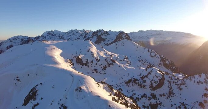 Snowed Alps summit in the Chamrousse peaks in France with sunrise rising, Aerial pan left shot