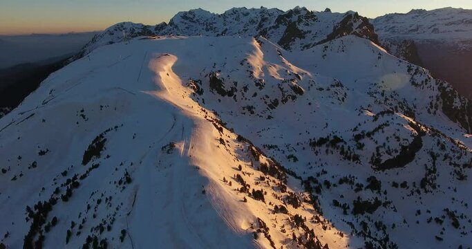 Snow capped summit of Chamrousse ski resort in the French Alps early sunrise, Aerial orbit around shot