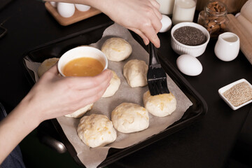 yeast dough ready for making homemade buns is on the table among other ingredients for baking bread. a woman prepares pastries, sifts flour.