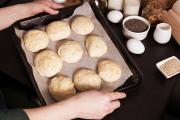 yeast dough ready for making homemade buns is on the table among other ingredients for baking bread. a woman prepares pastries, sifts flour.