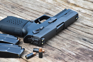Automatic black pistol, ammunition and cartridges on wooden table.