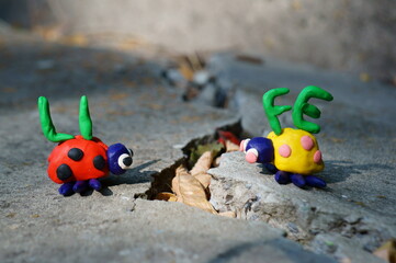 Obraz premium Figurines of two ladybirds made of plasticine. The figures are placed opposite each other. There's a crack between them. Next to it is the inscription life.