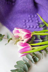 Beautiful bouquet of purple tulips with eucalyptus on a white chair along with a purple sweater. Spring mood, 8 March. Postcard for the holiday.