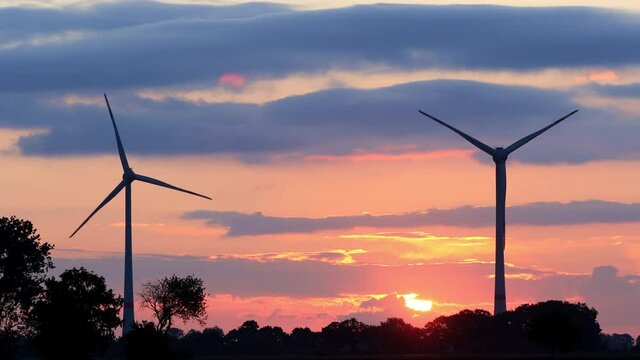 windmill turbines at sunset, orange sky
