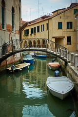 Venetian canal with bridge and moored motorboats