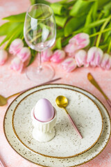 Easter table setting with pink tulip flowers and easter egg
