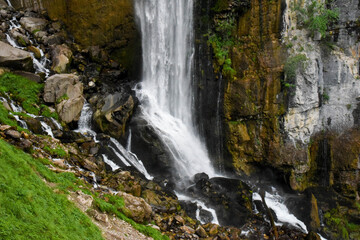 Fototapeta na wymiar Beautiful waterfall in switzerland rushing down a cliff and bursting onto a steep rocky mountainside