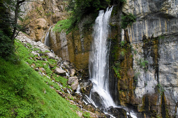 Fototapeta na wymiar Beautiful waterfall in switzerland rushing down a cliff and bursting onto a steep rocky mountainside