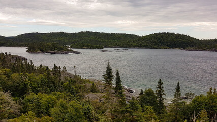 Scenic untouched landscape in the Pukaskwa Nationalpark. Mixed woodland surrounding a calm bay with waves washing around two wooded islands.