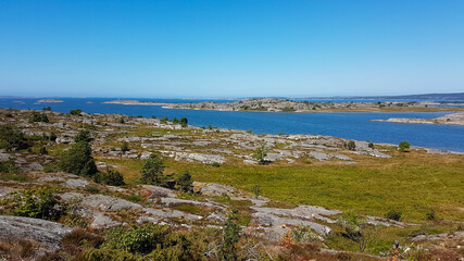 Fototapeta na wymiar Far scenic landscape showing a wide rocky grassland streaked by a calm bay