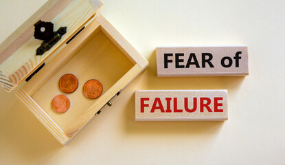 Fear of failure symbol. Wooden blocks with words 'fear of failure'. Beautiful white background, copy space. Small chest with coins. Business, fear of failure concept.