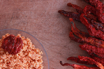 Cracked wheat (bulgur) pilaf with red chilies on wooden table.