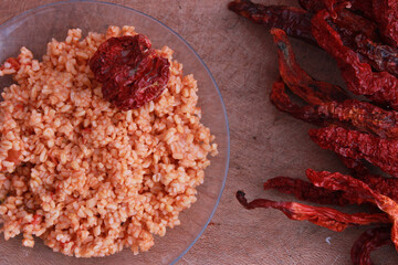 Cracked wheat (bulgur) pilaf with red chilies on wooden table.
