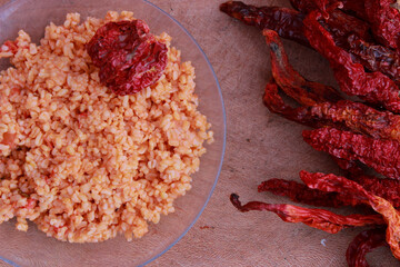 bulgur pilaf (cracked wheat) on wooden table with red chilies 