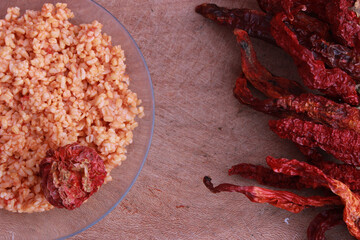 Cracked wheat (bulgur) pilaf with red chilies on wooden table.