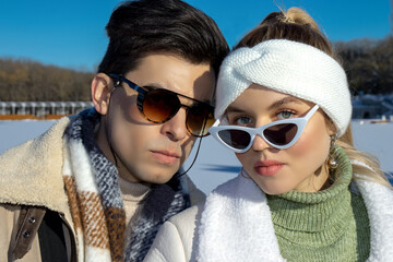 Portrait of a young couple in advertising style, wearing sunglasses and winter clothes on a cold...