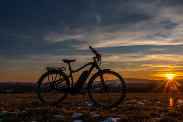 Black and gray electric bicycle in sunrise morning time on frosty field