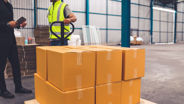Factory workers deliver boxes package on a pushing trolley in the warehouse . Industry supply chain management concept .