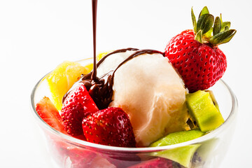 Vanilla ice cream in a glass with strawberry kiwi and oranges dices and dark chocolate