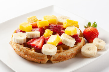 Waffle topped with strawberry banana and orange