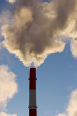 Huge clouds of steam from the pipes and boilers of the city Thermal Power Plant against the blue sky.