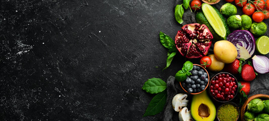 Healthy eating concept: vegetables and fruits on black stone background. Top view. Free space for...