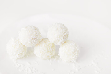 Fototapeta na wymiar Food photography of natural vegetarian raw food candies with coconut. Close-up white round coconut candy on a white, delicate and airy background. Empty space for text. Flat lay top-down.