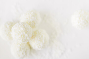 Food photography of natural vegetarian raw food candies with coconut. Close-up white round coconut candy on a white, delicate and airy background. Empty space for text. Flat lay top-down.