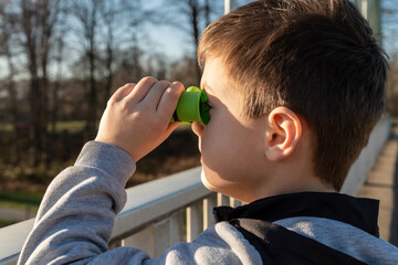 Ein Junge 7 schaut durch Fernglas von einer Kanalbr&uuml;cke